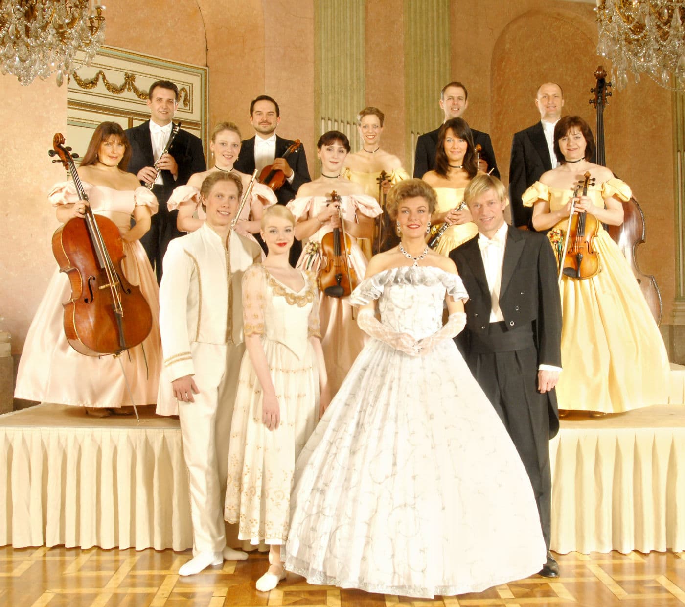 Musicisti e ballerini in abiti imperiali posano su una pedana decorata con sfondo elegante