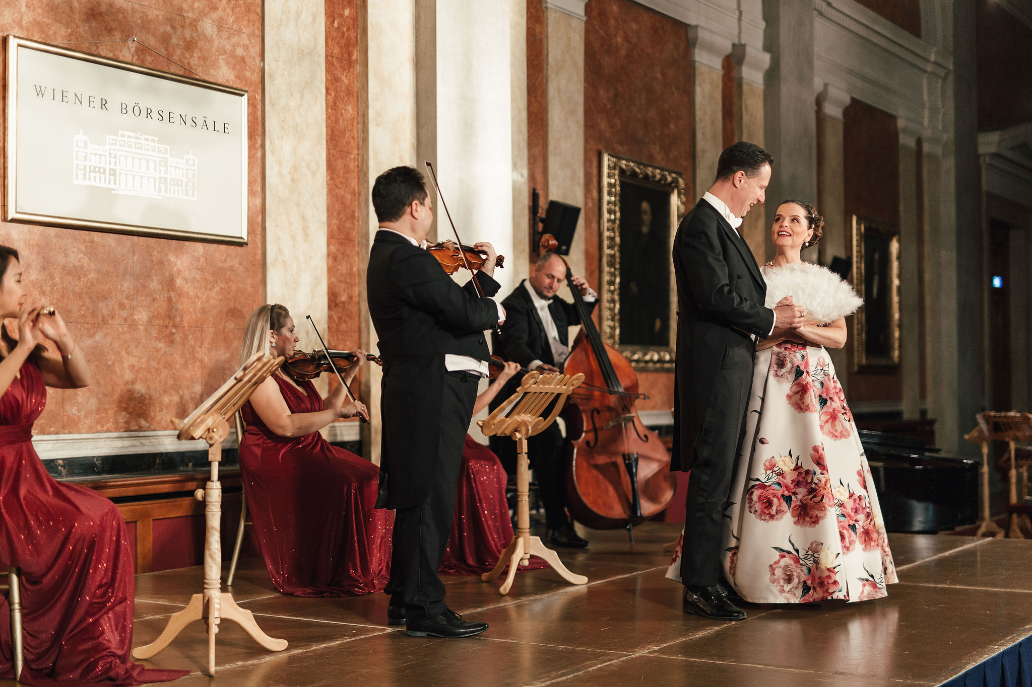 Coppia in abito da sera che danza sul palco della Börsensäle, con musicisti del Wiener Residenz Orchester in sottofondo.